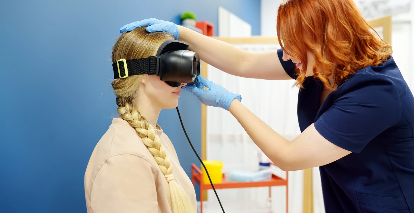 Woman receiving vestibular therapy with virtual reality headset, assisted by therapist in medical setting, emphasizing balance recovery and dizziness treatment in Greenwood Village, CO.
